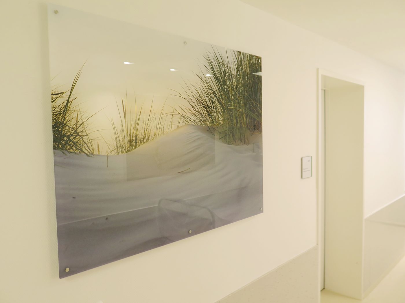 Acrylglasbild mit Dünenmotiv an sechs Edelstahl-Distanzhaltern in einem Krankenhausflur