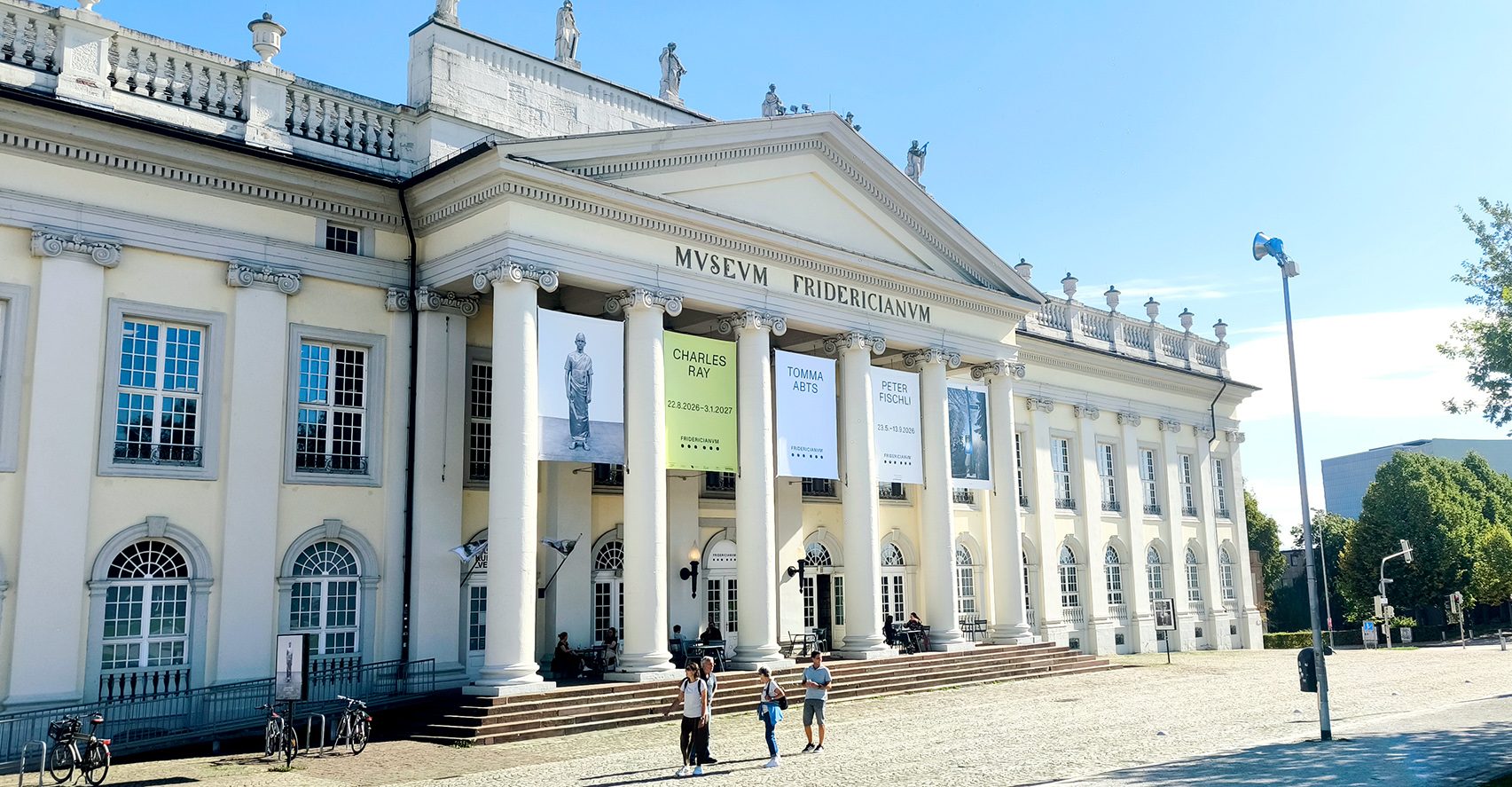 Frontansicht des Museum Fridericianum in Kassel mit fünf Ausstellungsbannern zwischen den Säulen
