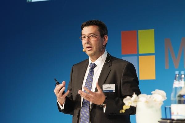 Redner auf einer Konferenzbühne vor einer blauen textilen Bespannung